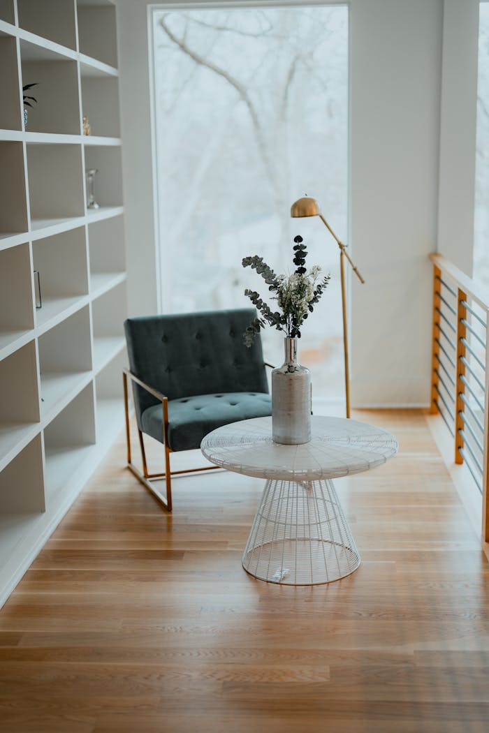 hero-img-02 Elegant interior featuring an armchair and centerpiece table with a plant, framed by a large window.