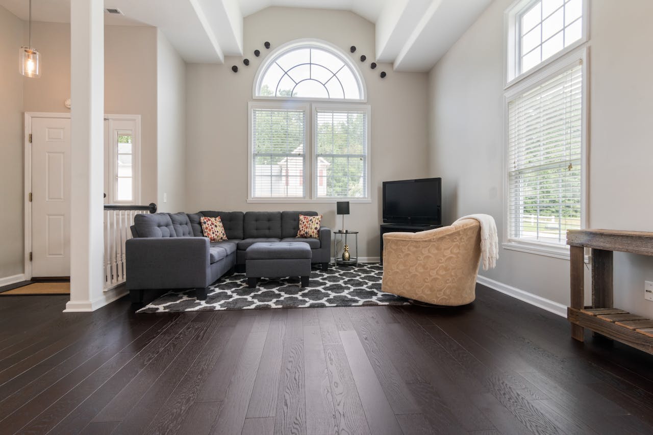 about-01 Bright living room with modern furniture, high ceilings, and big windows.